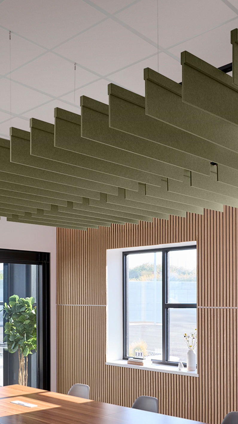 Green acoustic ceiling blade baffles suspended from the ceiling, installed in a conference room. Felt Right's acoustic blade baffles absorb 65% of sound waves, making office spaces quieter and feel more calm.