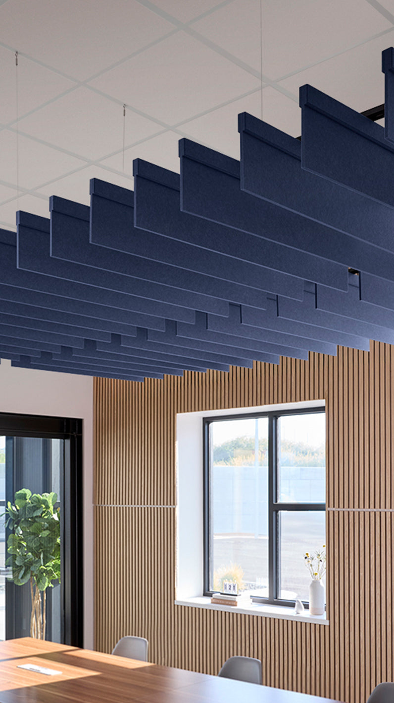 Dark blue acoustic ceiling blade baffles suspended from the ceiling, installed in a conference room. Felt Right's acoustic blade baffles absorb 65% of sound waves, making office spaces quieter and feel more calm.