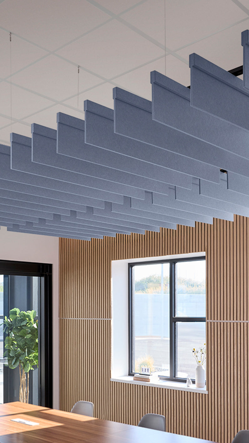Purplish-blue acoustic ceiling blade baffles suspended from the ceiling, installed in a conference room. Felt Right's acoustic blade baffles absorb 65% of sound waves, making office spaces quieter and feel more calm.