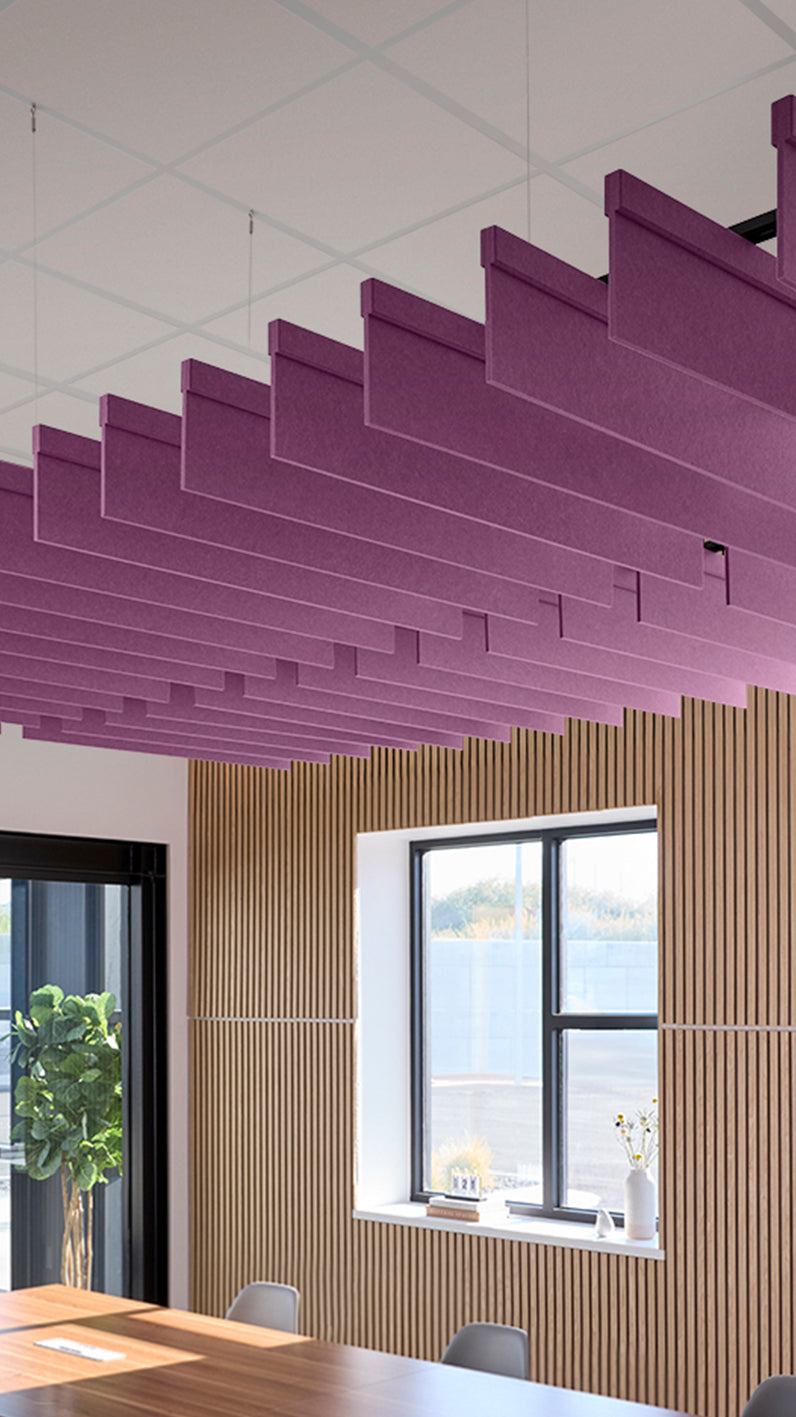 Reddish-purple acoustic ceiling blade baffles suspended from the ceiling, installed in a conference room. Felt Right's acoustic blade baffles absorb 65% of sound waves, making office spaces quieter and feel more calm.