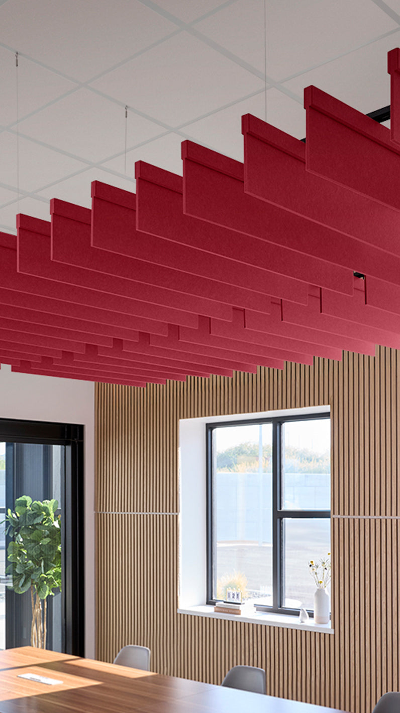 Red acoustic ceiling blade baffles suspended from the ceiling, installed in a conference room. Felt Right's acoustic blade baffles absorb 65% of sound waves, making office spaces quieter and feel more calm.