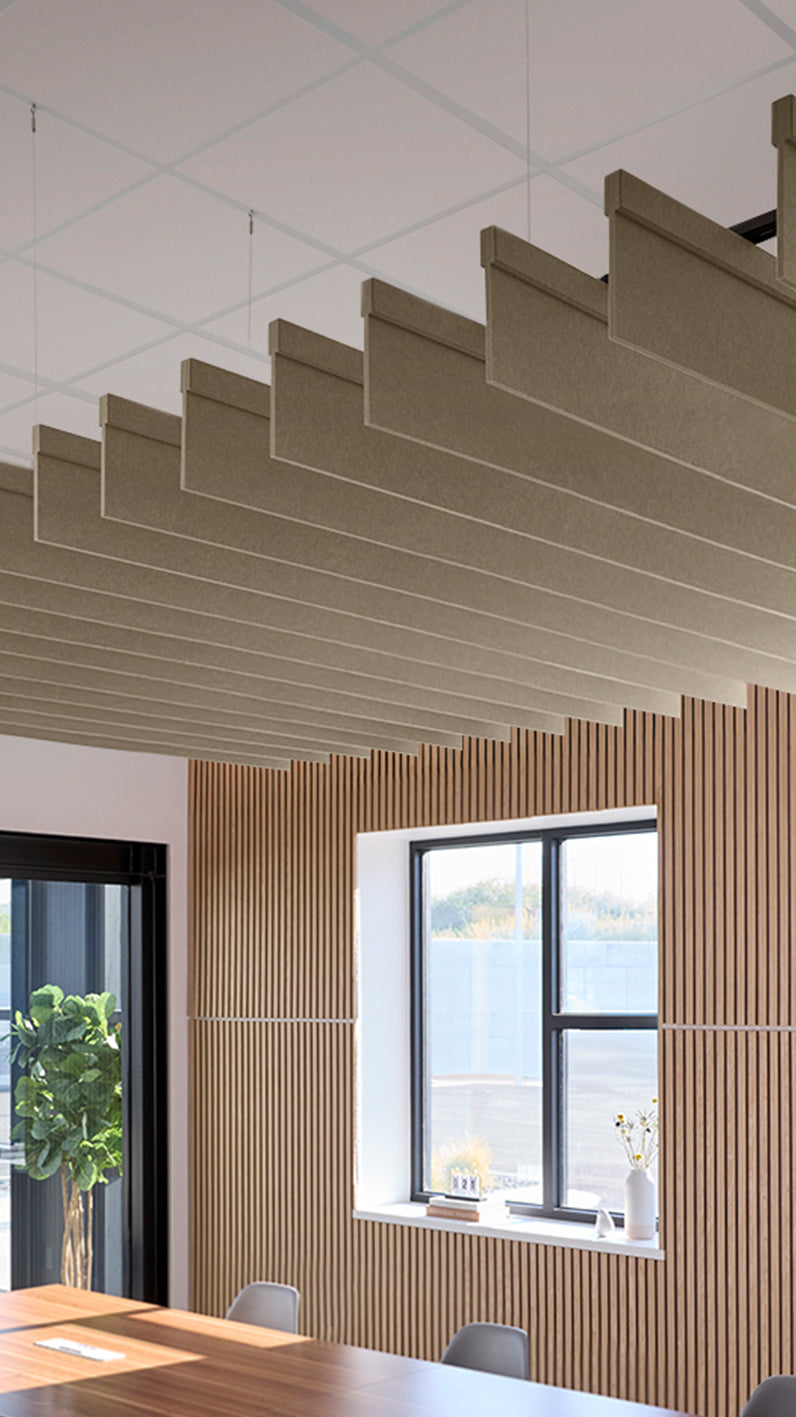 Light brown acoustic ceiling blade baffles suspended from the ceiling, installed in a conference room. Felt Right's acoustic blade baffles absorb 65% of sound waves, making office spaces quieter and feel more calm.