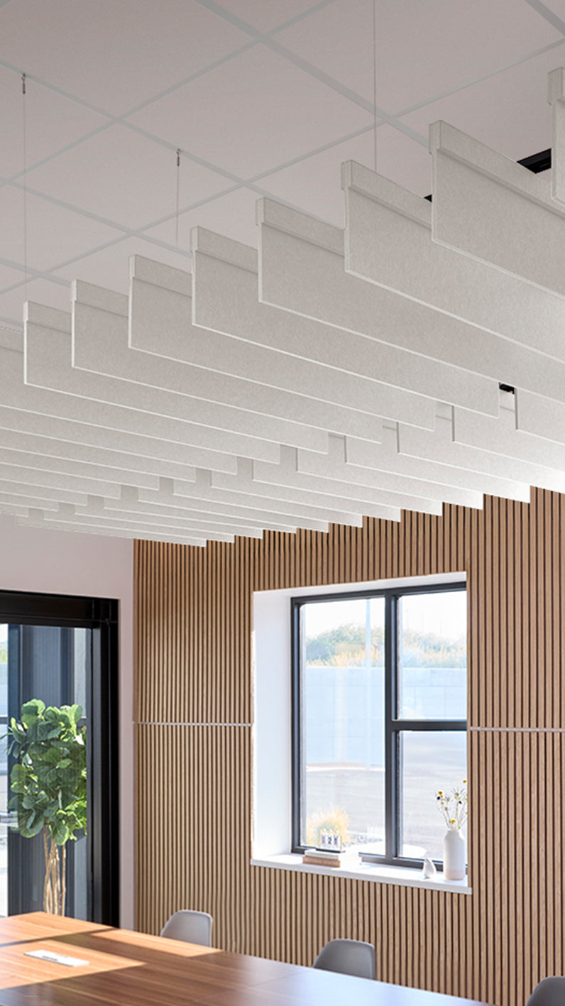 White acoustic ceiling blade baffles suspended from the ceiling, installed in a conference room. Felt Right's acoustic blade baffles absorb 65% of sound waves, making office spaces quieter and feel more calm.