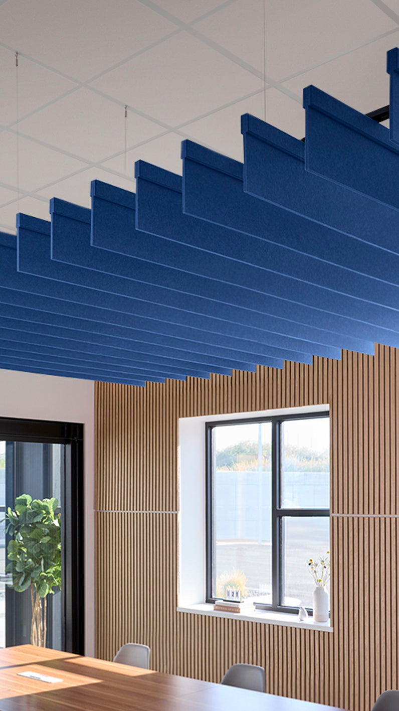 Blue acoustic ceiling blade baffles suspended from the ceiling, installed in a conference room. Felt Right's acoustic blade baffles absorb 65% of sound waves, making office spaces quieter and feel more calm.