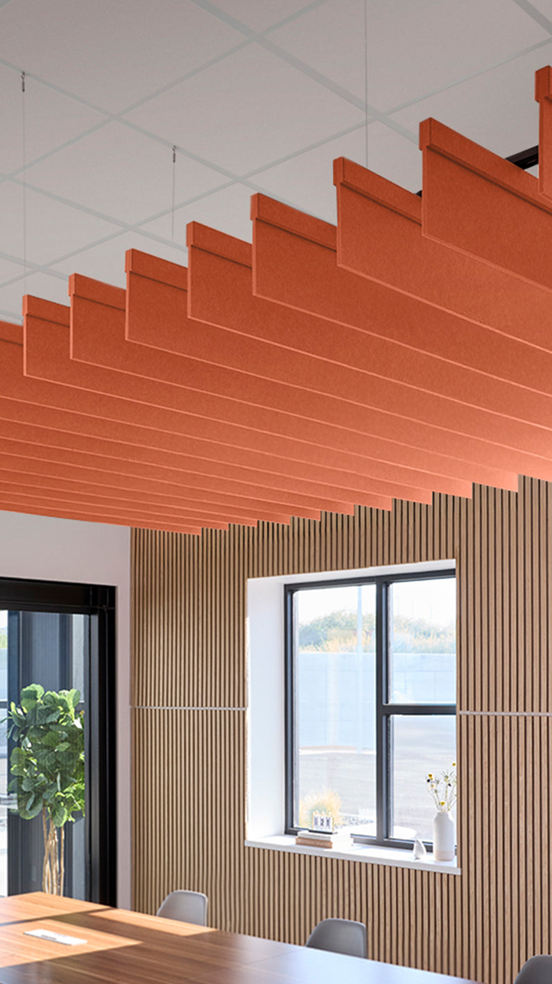 Orange acoustic ceiling blade baffles suspended from the ceiling, installed in a conference room. Felt Right's acoustic blade baffles absorb 65% of sound waves, making office spaces quieter and feel more calm.