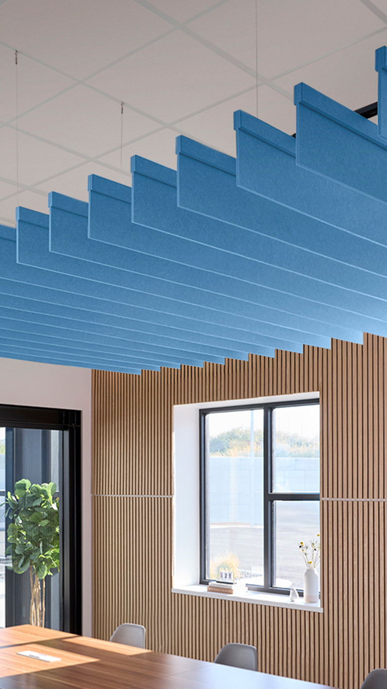 Bright blue acoustic ceiling blade baffles suspended from the ceiling, installed in a conference room. Felt Right's acoustic blade baffles absorb 65% of sound waves, making office spaces quieter and feel more calm.