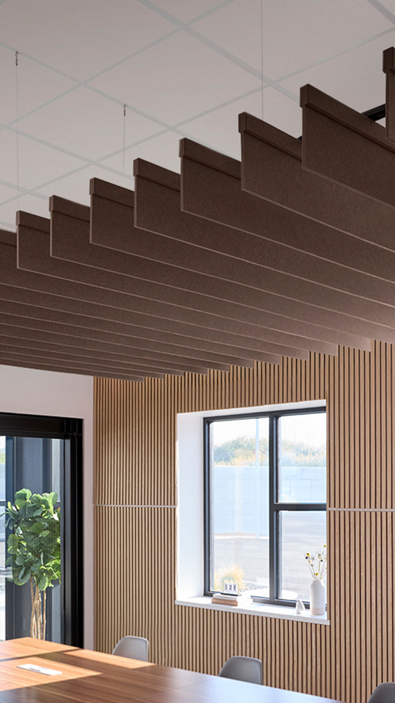 Brown acoustic ceiling blade baffles suspended from the ceiling, installed in a conference room. Felt Right's acoustic blade baffles absorb 65% of sound waves, making office spaces quieter and feel more calm.
