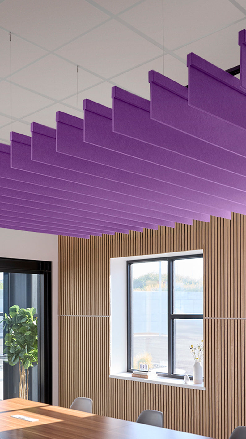 Purple acoustic ceiling blade baffles suspended from the ceiling, installed in a conference room. Felt Right's acoustic blade baffles absorb 65% of sound waves, making office spaces quieter and feel more calm.