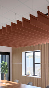 Reddish-brown acoustic ceiling blade baffles suspended from the ceiling, installed in a conference room. Felt Right's acoustic blade baffles absorb 65% of sound waves, making office spaces quieter and feel more calm.