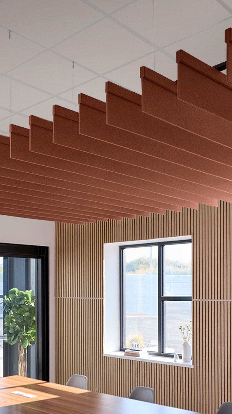 Reddish-brown acoustic ceiling blade baffles suspended from the ceiling, installed in a conference room. Felt Right's acoustic blade baffles absorb 65% of sound waves, making office spaces quieter and feel more calm.