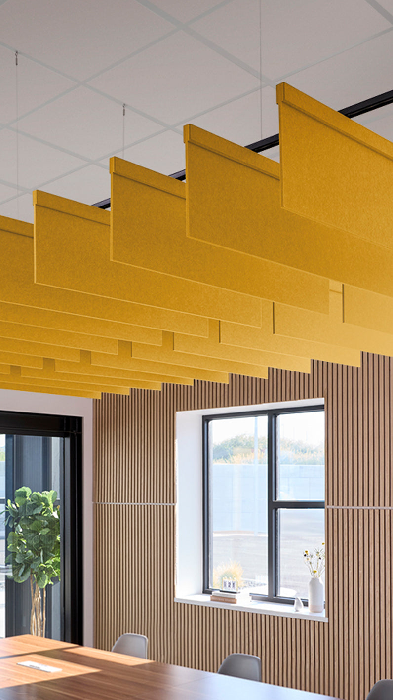 Dark yellow acoustic ceiling blade baffles suspended from the ceiling, installed in a conference room. Felt Right's acoustic blade baffles absorb 65% of sound waves, making office spaces quieter and feel more calm.