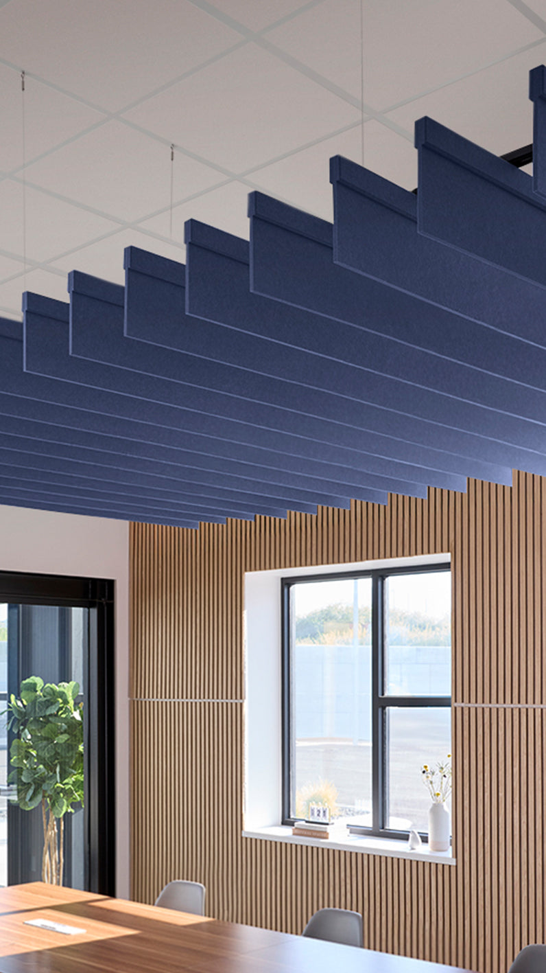 Dark blue acoustic ceiling blade baffles suspended from the ceiling, installed in a conference room. Felt Right's acoustic blade baffles absorb 65% of sound waves, making office spaces quieter and feel more calm.