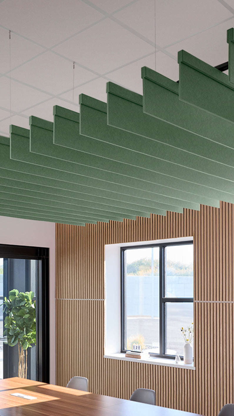 Green acoustic ceiling blade baffles suspended from the ceiling, installed in a conference room. Felt Right's acoustic blade baffles absorb 65% of sound waves, making office spaces quieter and feel more calm.