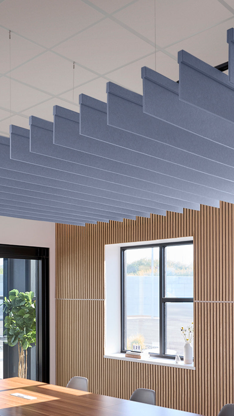 Purplish-blue acoustic ceiling blade baffles suspended from the ceiling, installed in a conference room. Felt Right's acoustic blade baffles absorb 65% of sound waves, making office spaces quieter and feel more calm.
