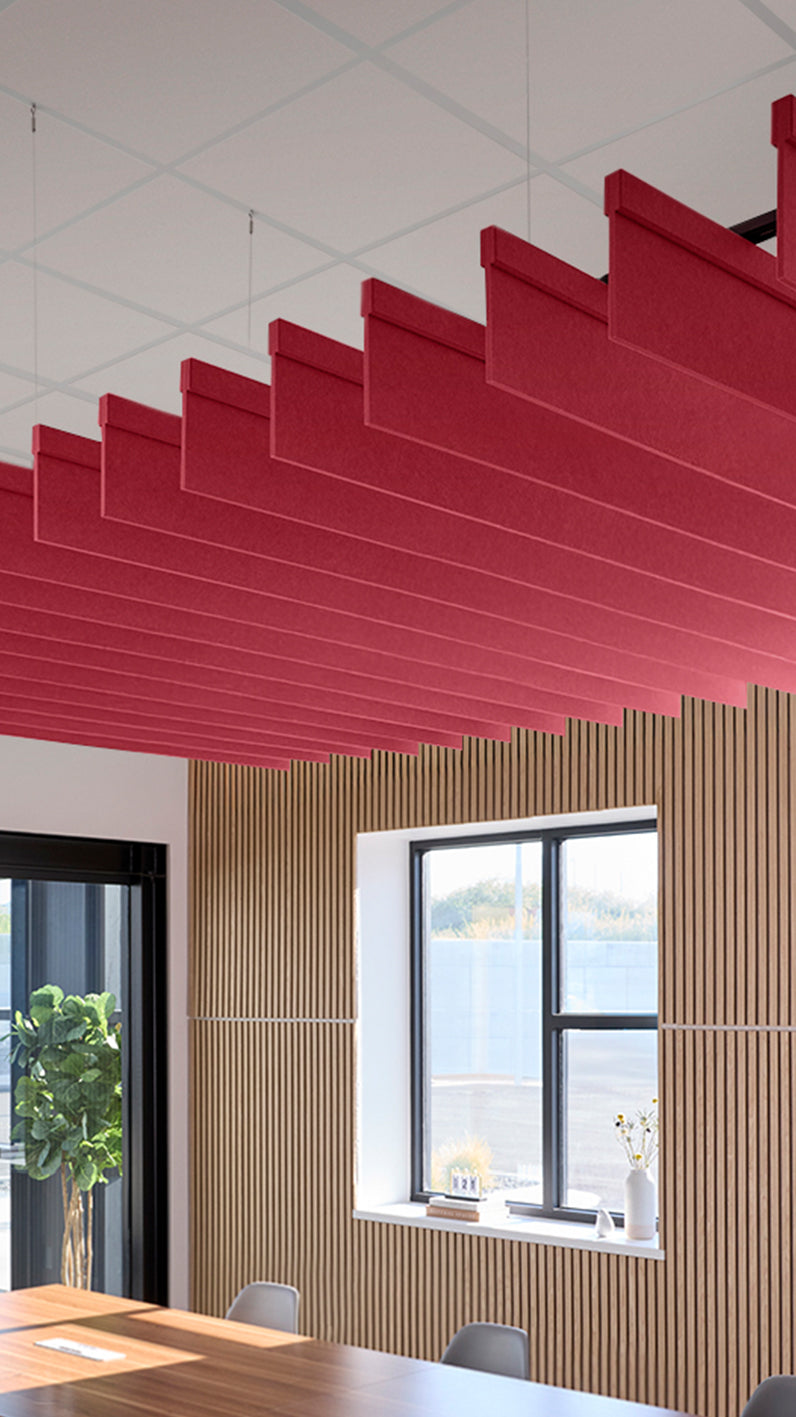 Red acoustic ceiling blade baffles suspended from the ceiling, installed in a conference room. Felt Right's acoustic blade baffles absorb 65% of sound waves, making office spaces quieter and feel more calm.