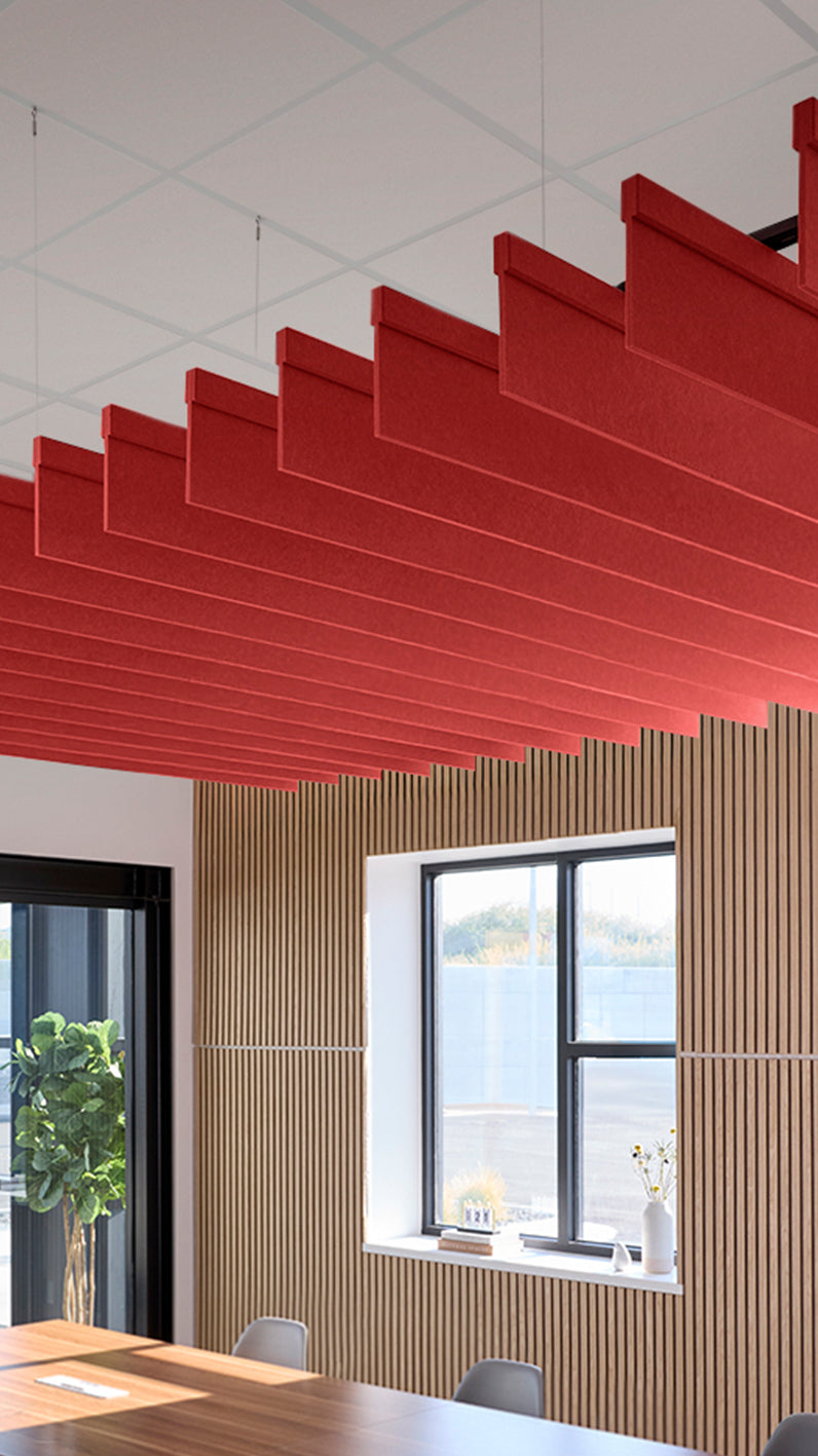 Bright red acoustic ceiling blade baffles suspended from the ceiling, installed in a conference room. Felt Right's acoustic blade baffles absorb 65% of sound waves, making office spaces quieter and feel more calm.