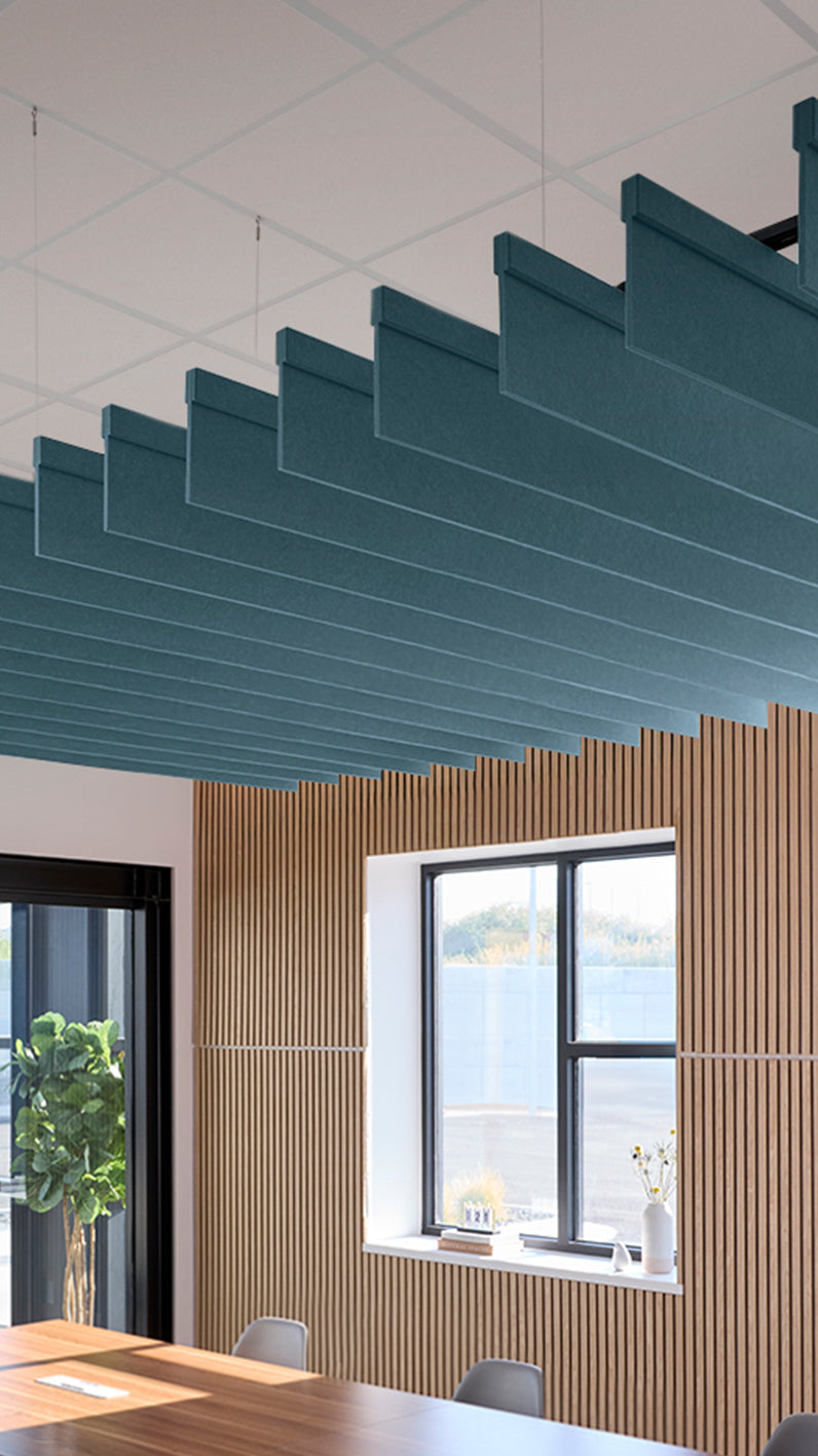 Teal acoustic ceiling blade baffles suspended from the ceiling, installed in a conference room. Felt Right's acoustic blade baffles absorb 65% of sound waves, making office spaces quieter and feel more calm.
