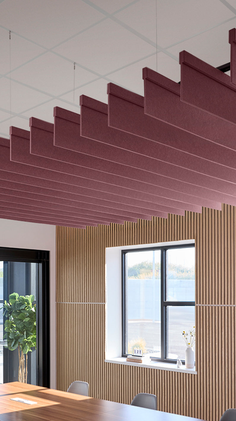 Deep reddish-purple acoustic ceiling blade baffles suspended from the ceiling, installed in a conference room. Felt Right's acoustic blade baffles absorb 65% of sound waves, making office spaces quieter and feel more calm.