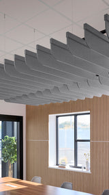 Multiple gray curved acoustic baffles suspended from ceiling in modern office space with wooden wall panels.