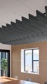 Multiple dark curved acoustic baffles suspended from ceiling grid above wood-paneled wall with window.