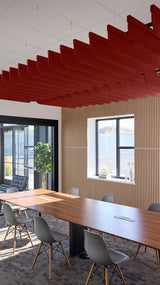 Red fin-shaped acoustic baffles suspended from ceiling in modern office conference room with wooden table and chairs.
