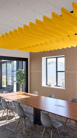 Yellow acoustic fin baffles suspended from ceiling in modern office conference room with wooden table and chairs.
