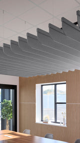 Dark gray curved acoustic baffles suspended from ceiling grid above wooden wall paneling and interior space.
