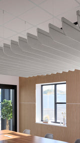 Gray curved acoustic baffles suspended from ceiling grid in modern office space with wood paneling.