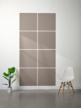 Decorative wall panels with geometric pattern on a white wall, accompanied by a plant and chair.