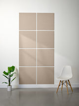 Beige acoustic panels on a wall with a white chair and plant in a minimalistic room.