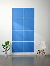Blue wall art with geometric design on a white wall, accompanied by a plant and chair.