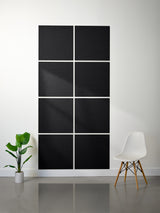 Abstract black and white wall art in a modern room with a plant and chair.