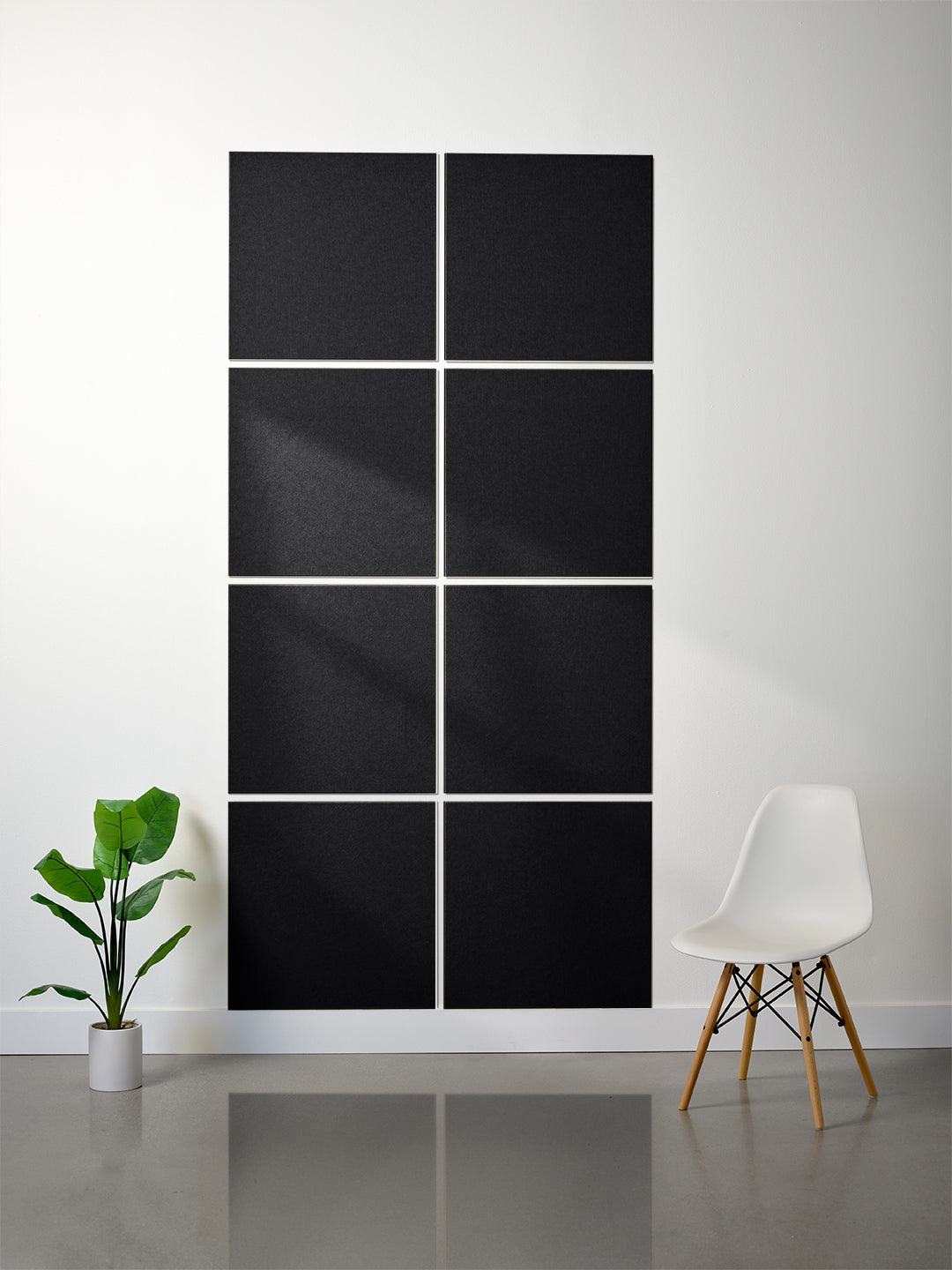 Abstract black and white wall art in a modern room with a plant and chair.