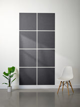 Wall with decorative black panels and a white chair in a minimalistic room.