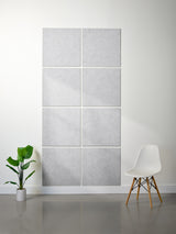 Gray acoustic panels on a wall with a white chair and plant in a minimalistic room.