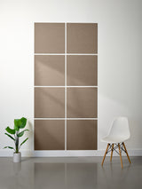 Brown acoustic panels on a white wall with a plant and chair in the foreground