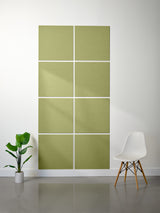 Green acoustic panels on a white wall with a plant and chair in the foreground