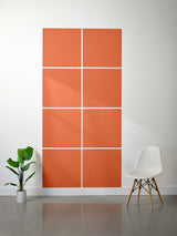 Orange acoustic panels on a white wall with a plant and chair in the foreground