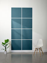 Blue textured wall panels on a white wall with a plant and chair in the foreground.