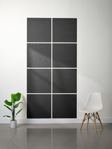 Black acoustic panels on a white wall with a plant and chair in the foreground.