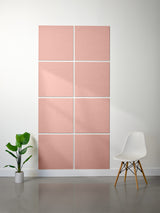 Pink acoustic panels on a wall with a white chair and plant in a minimalistic room.