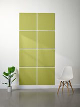 Green acoustic panels on a white wall with a plant and chair in the foreground