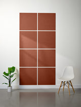 Brown acoustic panels on a white wall with a white chair and plant in the foreground.