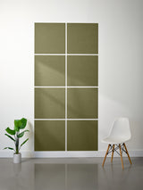 Green acoustic panels on a white wall with a plant and chair in the foreground