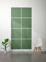 Green acoustic panels on a white wall with a plant and chair in the foreground