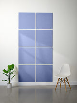 Blue wall art with geometric design in a minimalistic room with a plant and chair.