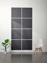 Eight dark gray tiles with vertical parallel line engraving arranged in a 2x4 grid on a white wall.