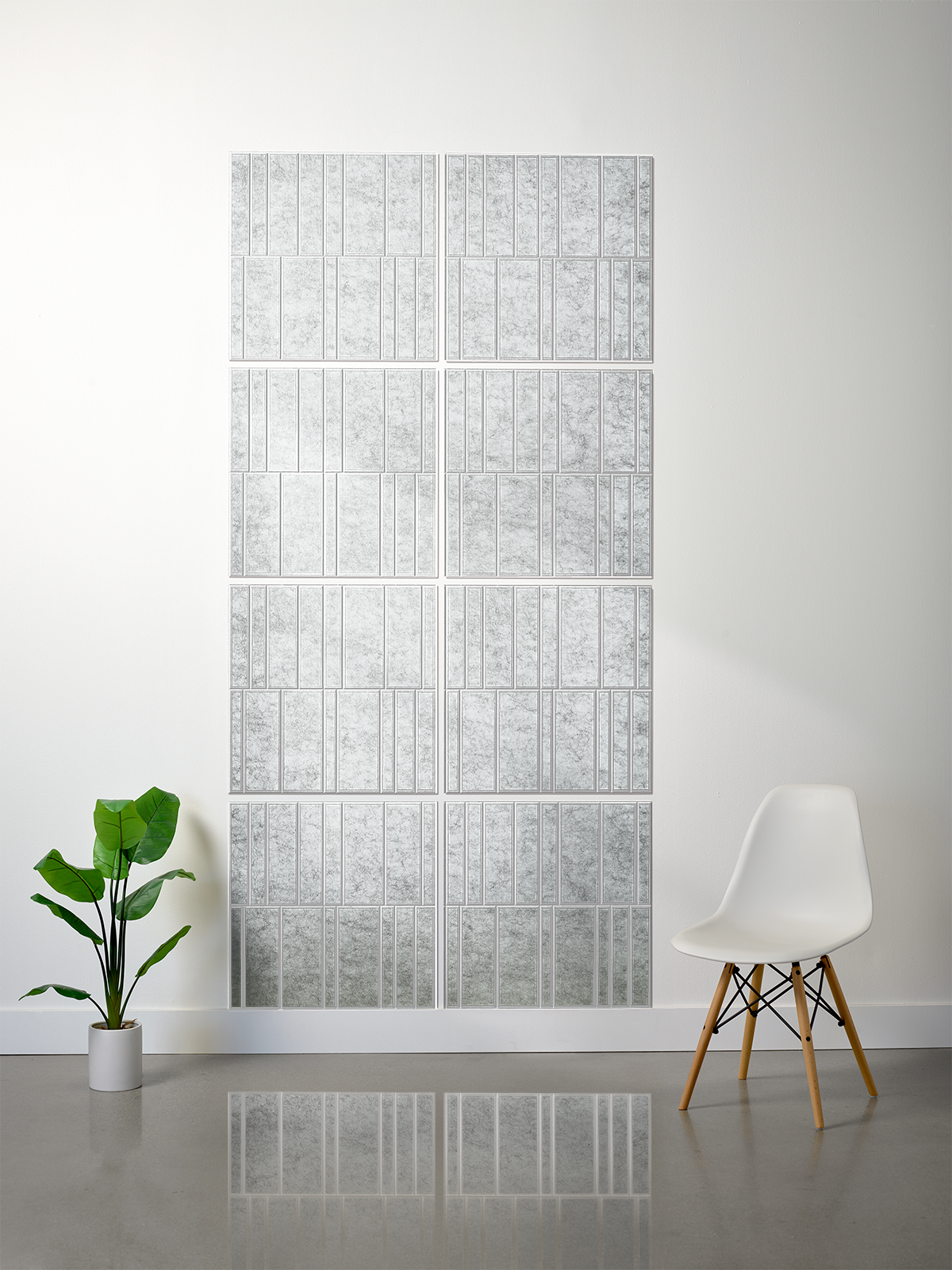 A 12-panel wall mirror set with a textured silver and white marble pattern, styled in a minimalist room with a white chair and a green potted plant.