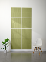 Four green tiles with vertical engraved lines arranged in a 2x2 offset pattern on a wall.
