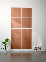 Four terracotta tiles with vertical engraved line pattern arranged in offset configuration on white wall.